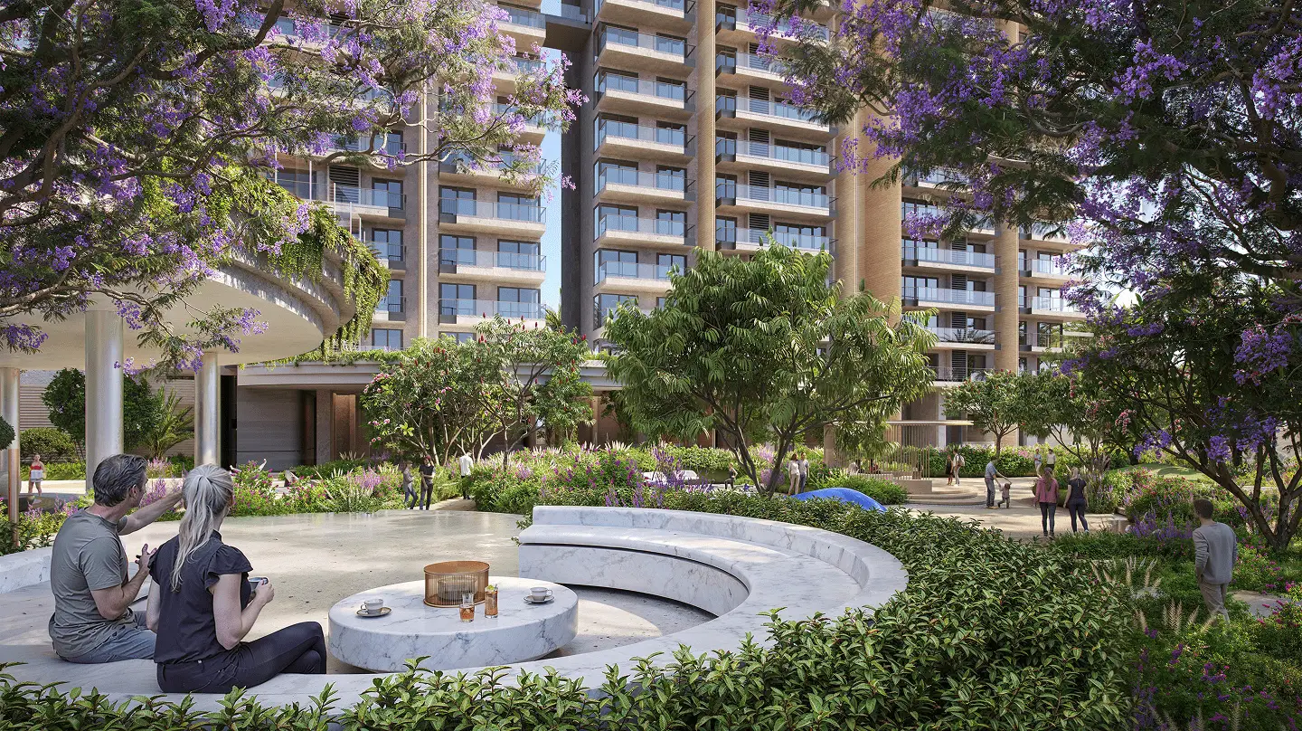 Couple sitting on a curved stone bench in a landscaped garden with modern buildings behind.