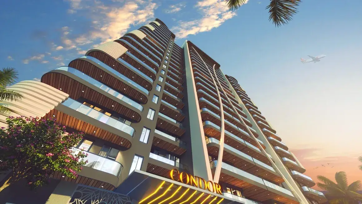 View of a modern residential building with curved balconies and lush greenery in the foreground.