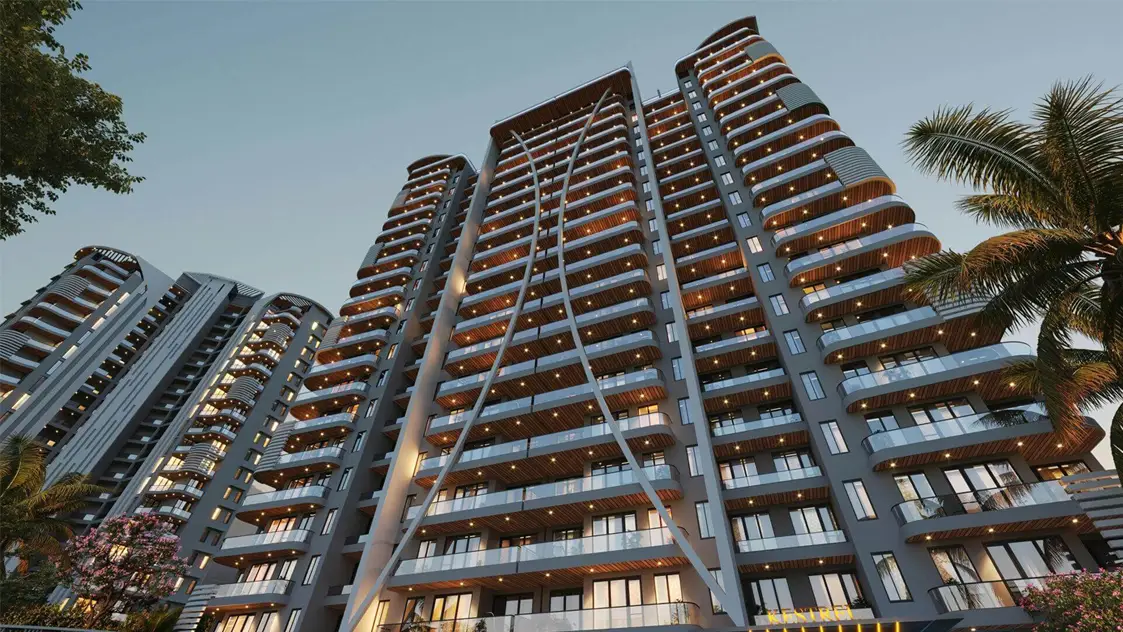 Tall residential building with curved balconies and large windows, surrounded by palm trees.