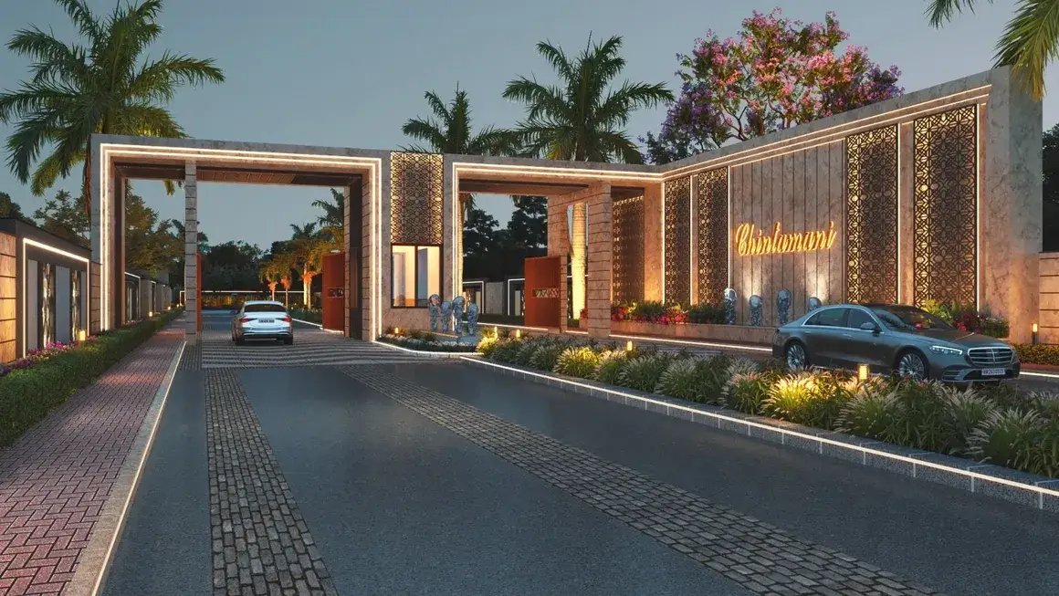 Illuminated entrance of Chintamani with palm trees and decorative landscaping at dusk.