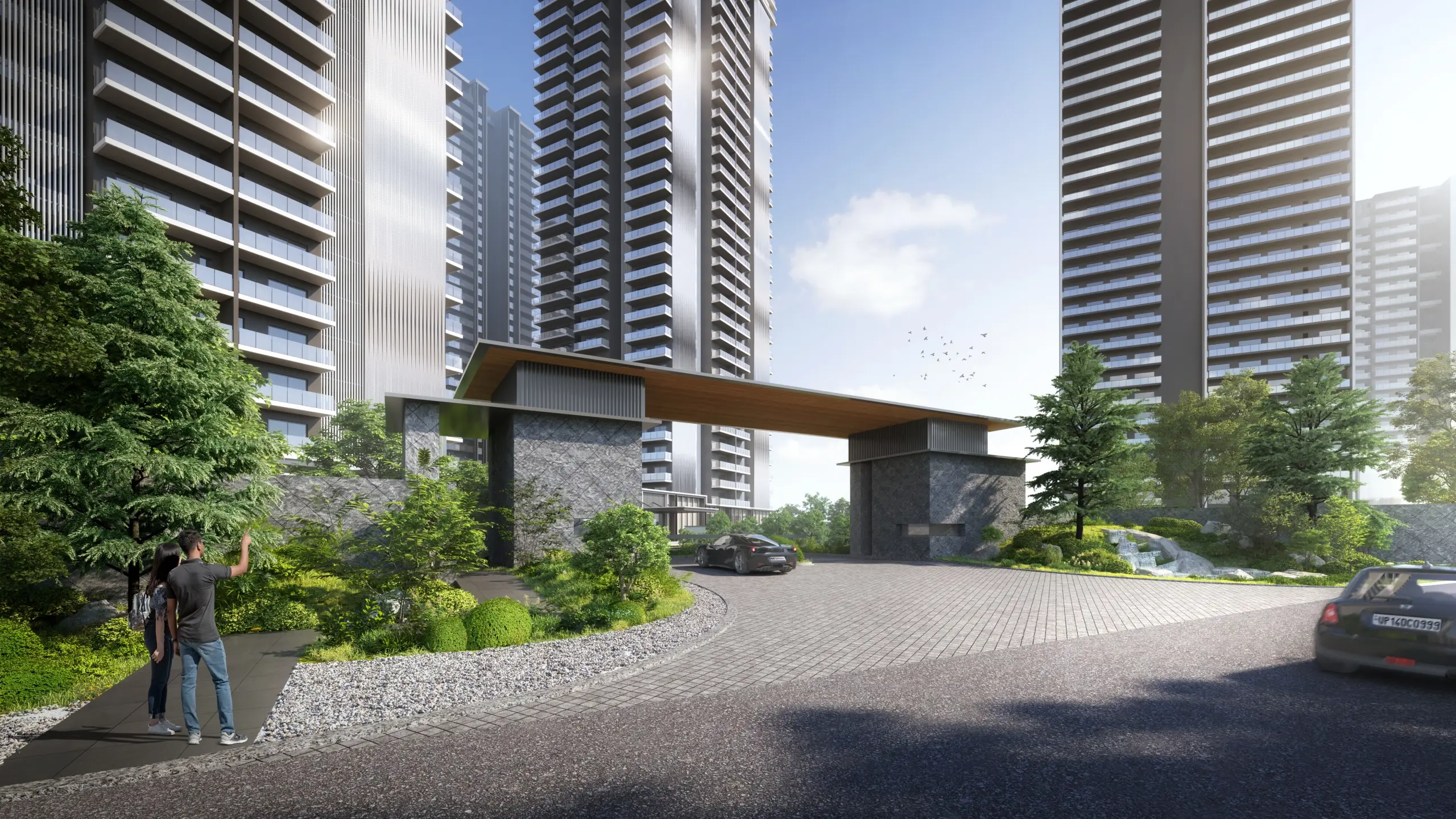 Modern residential entrance with two tall buildings, landscaped greenery, and a curved driveway.
