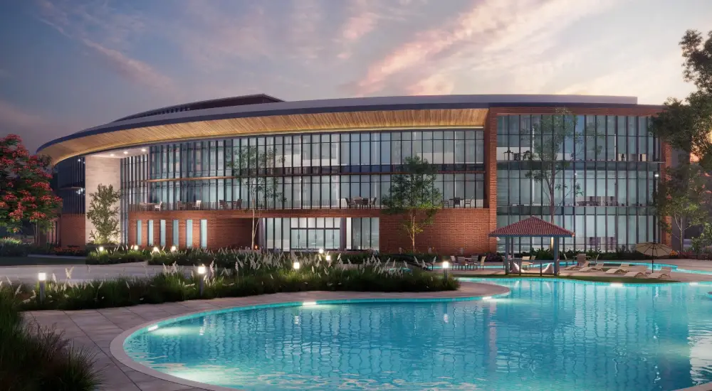 Modern clubhouse with large glass windows, surrounded by a pool and landscaped gardens.