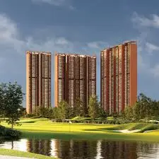 Three tall residential buildings with modern architecture near a green landscape and water body.