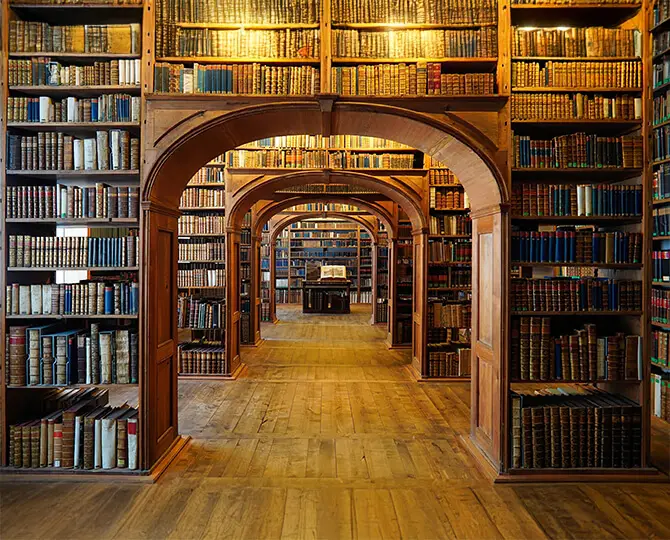 Wooden shelves filled with books, archways leading to a central reading table.