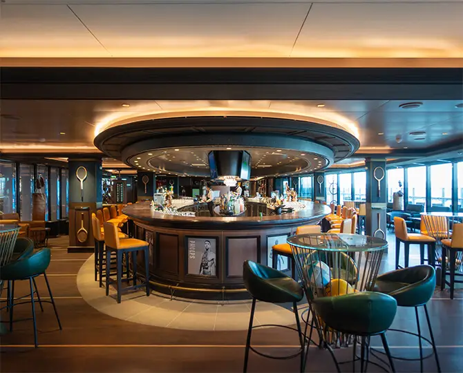 Modern sports bar interior with circular bar, colorful seating, and large windows.