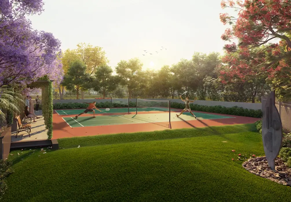 Two players on a tennis court surrounded by greenery and blooming flowers at sunset.
