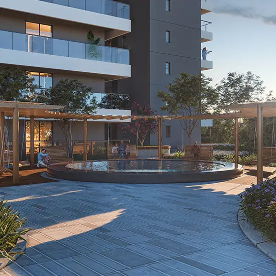 A circular pool surrounded by wooden seating and plants near a modern building.