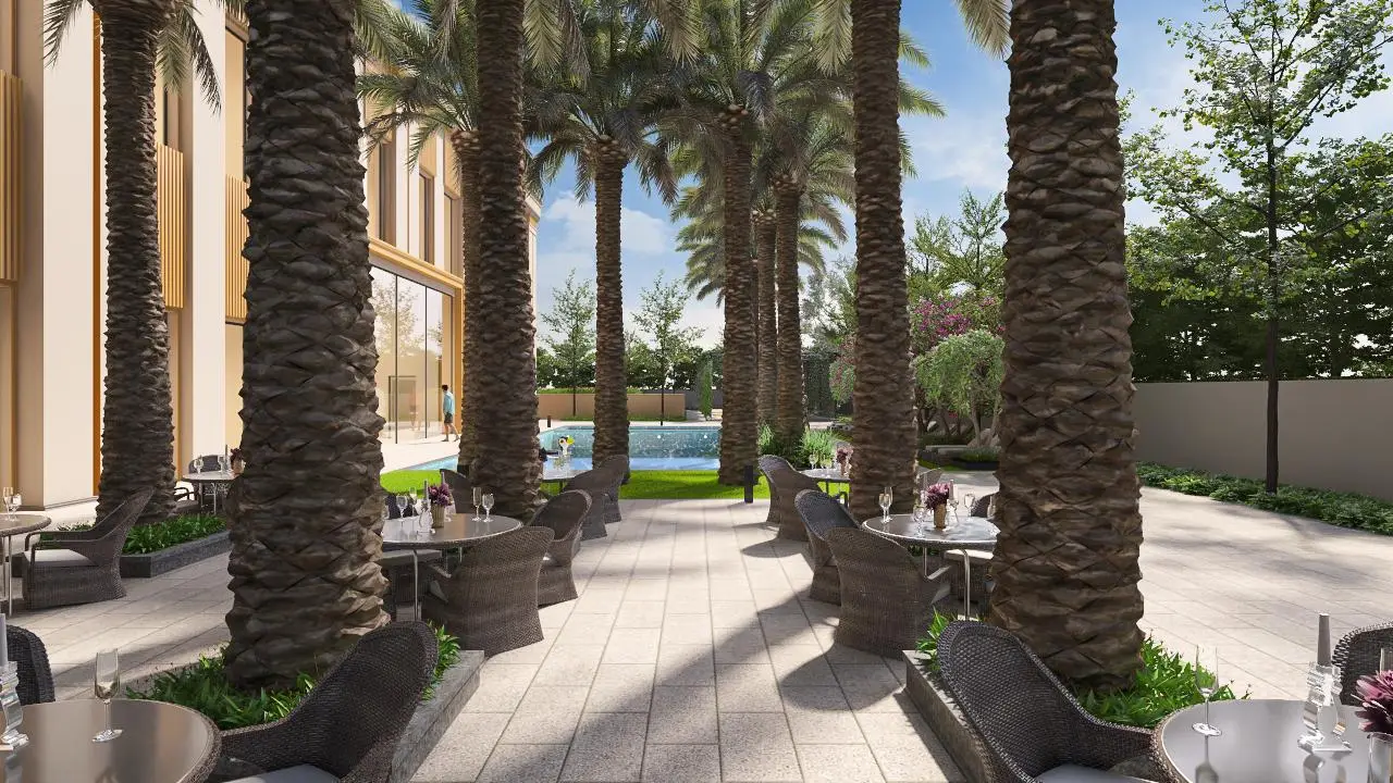 A serene patio area with palm trees, tables, and a swimming pool in the background.