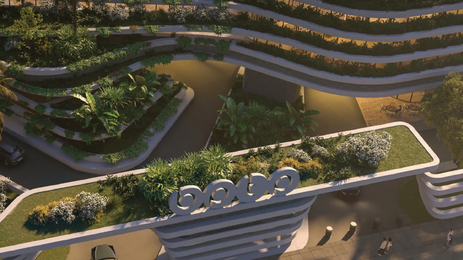 Aerial view of a building with green terraces, lush plants, and curved design elements.