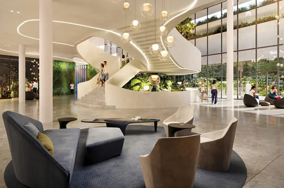 Spacious lobby with a spiral staircase, modern seating, and greenery in large windows.
