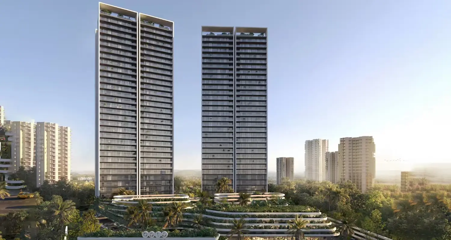 Two tall residential towers with glass facades surrounded by greenery and smaller buildings in the background.