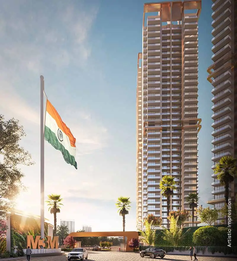Modern residential towers with Indian flag, palm trees, and entrance gate in a bright sky.