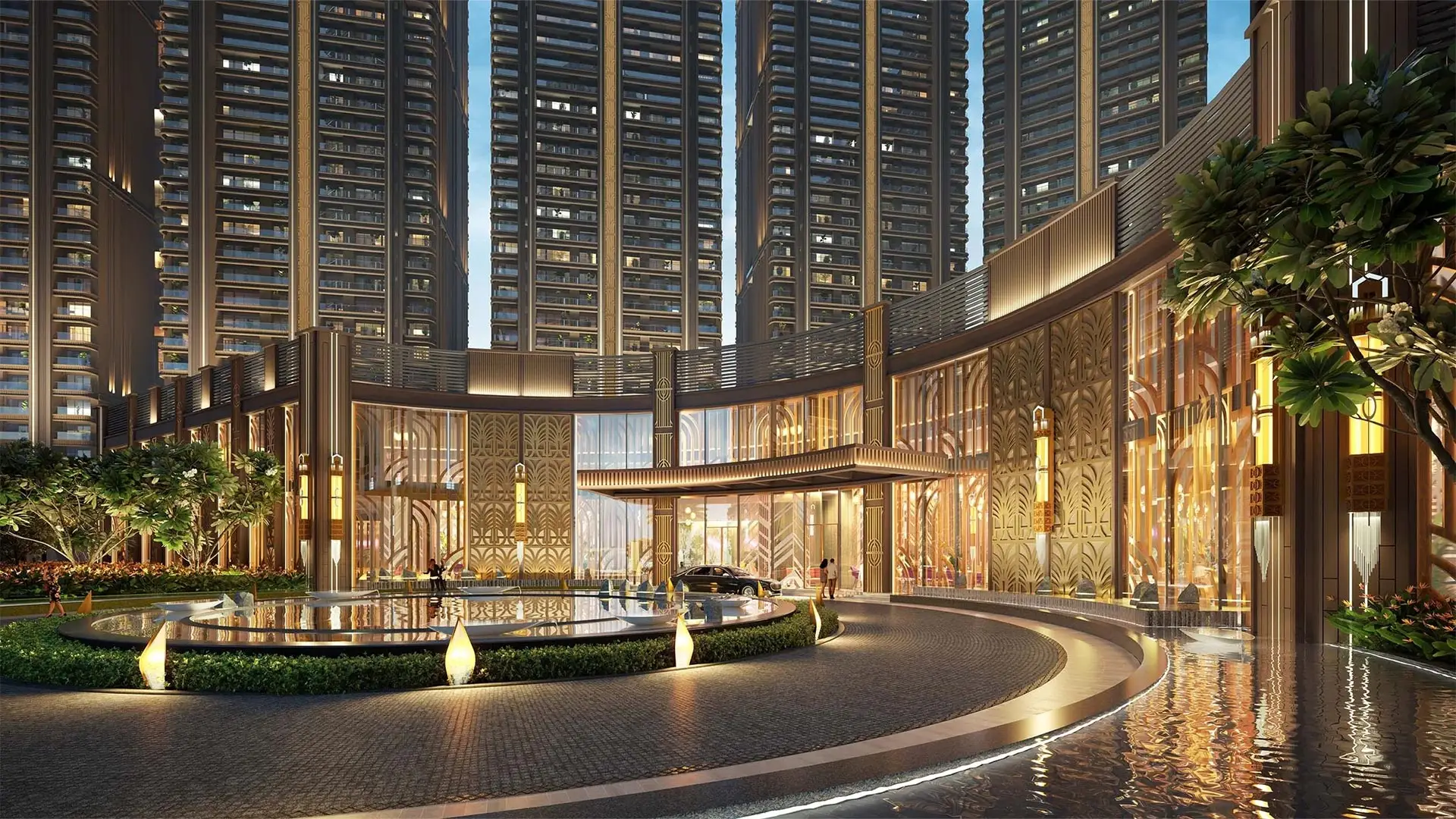A luxurious building entrance with water features, greenery, and tall residential towers in the background.