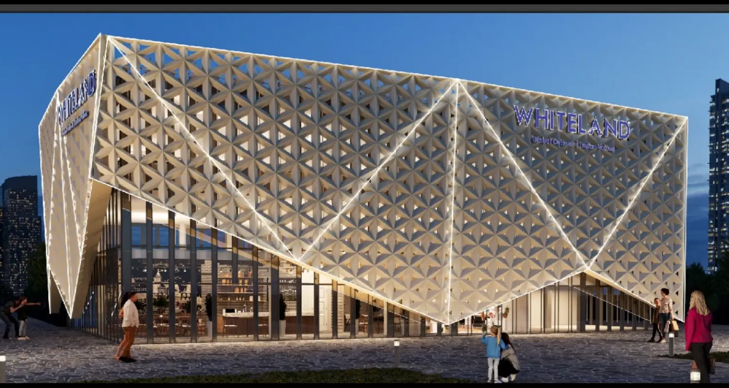 Modern architectural building with triangular facade, illuminated signage, and people walking nearby.
