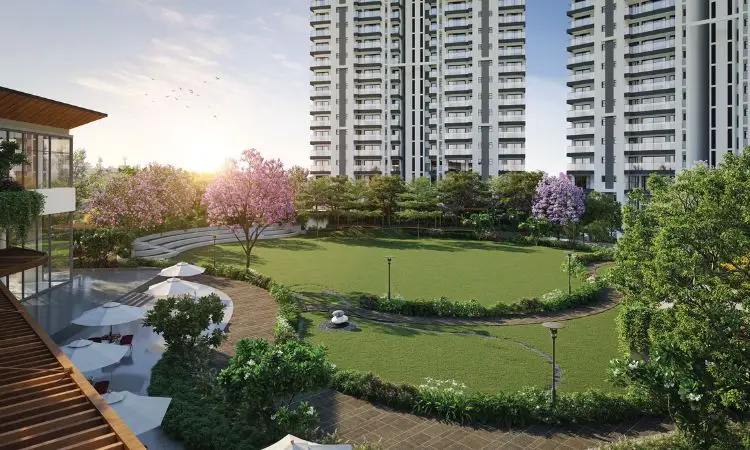 Modern residential buildings surround a landscaped area with trees and flowers, featuring a lawn and seating.