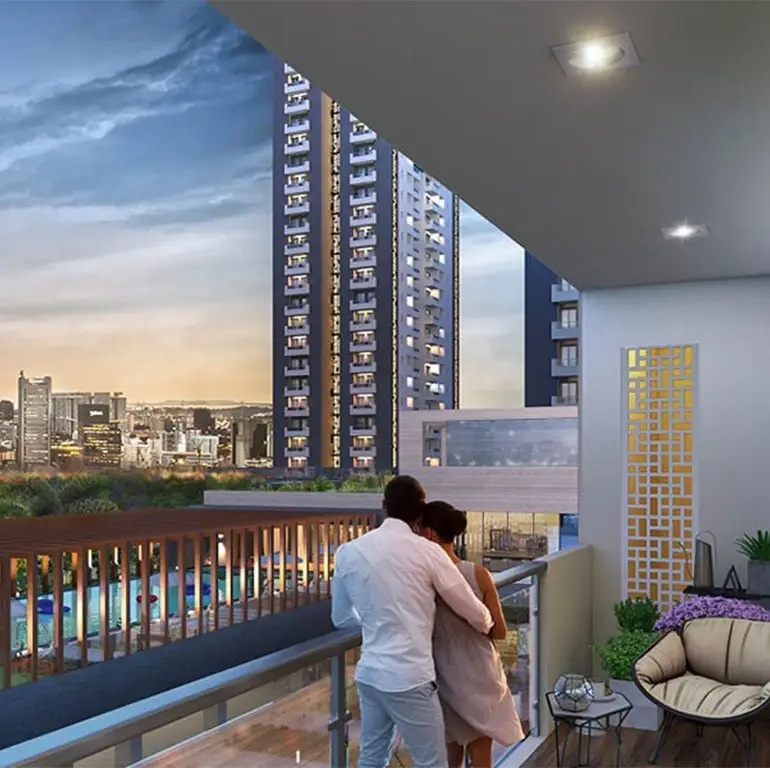 Couple embracing on a balcony overlooking a city skyline with modern buildings and a pool.