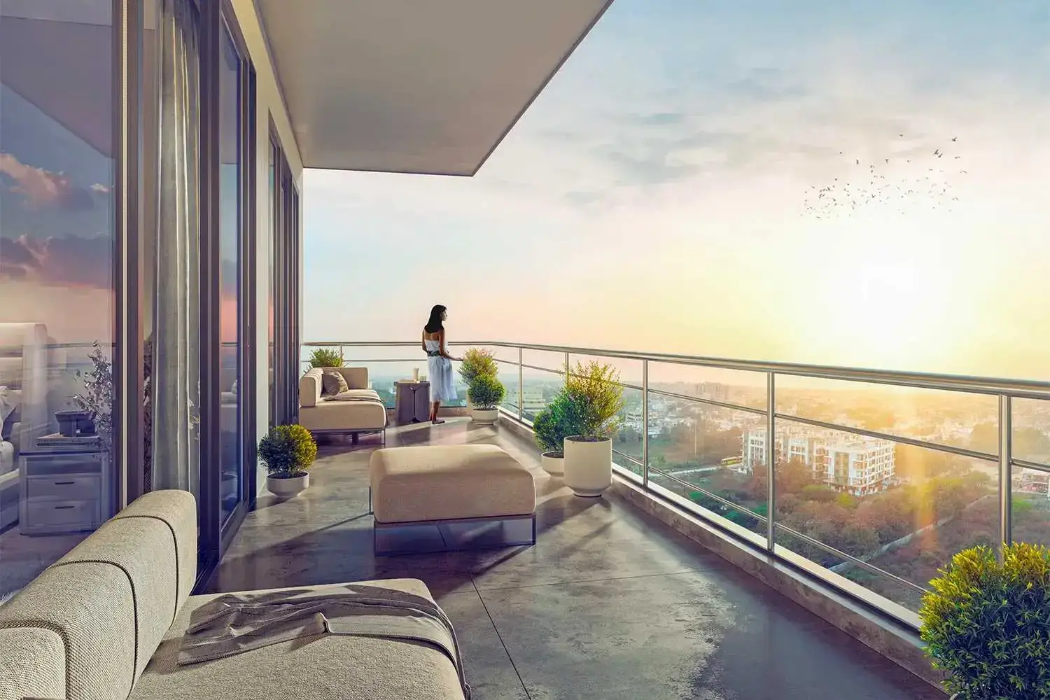 Modern balcony with seating, plants, and a woman overlooking a sunset view.