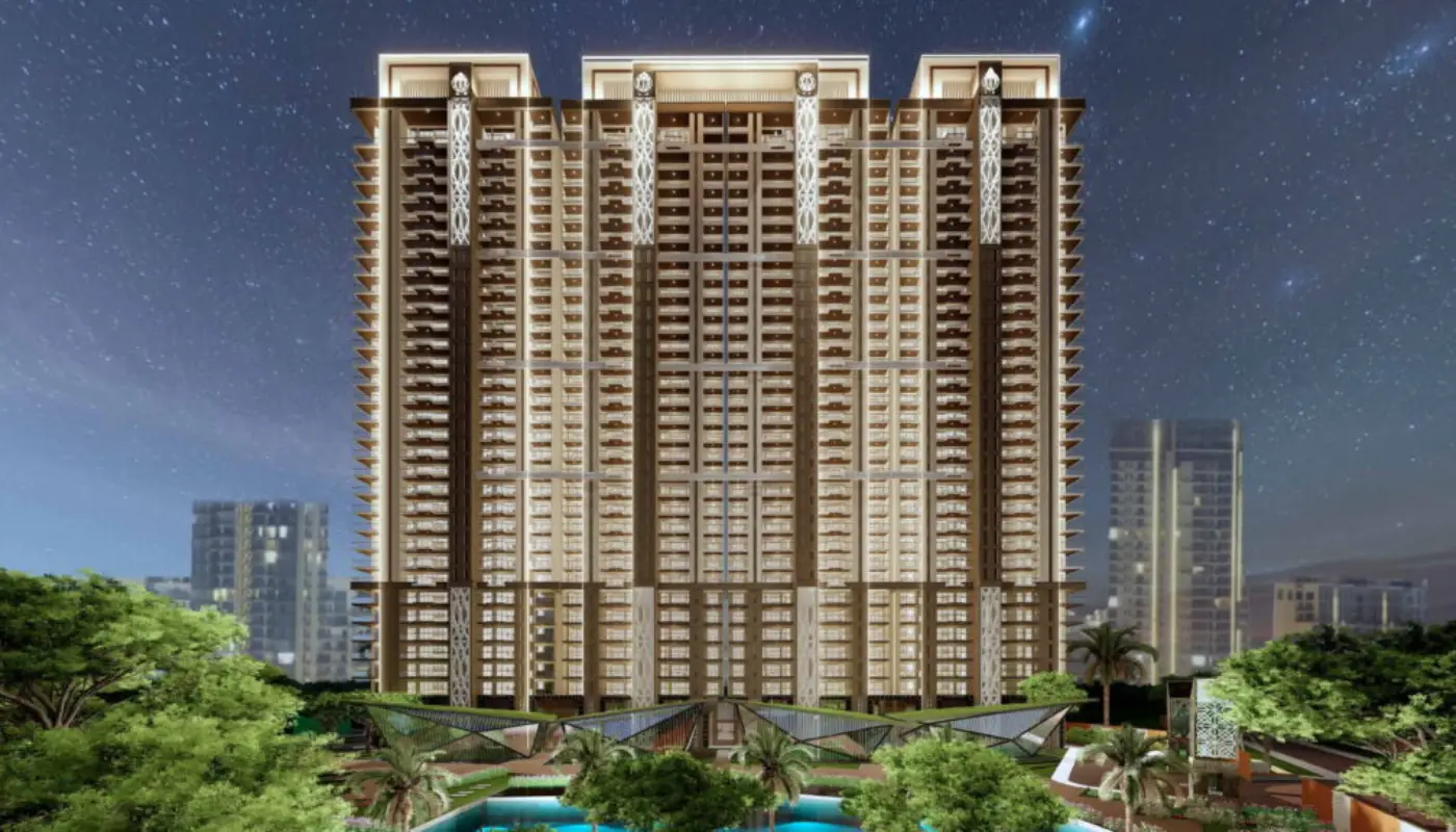 Tall residential building with modern design, surrounded by greenery and a pool area at night.