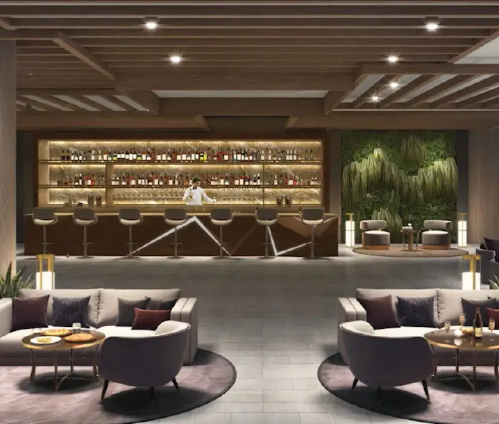 Modern lounge with a bar, seating areas, and greenery, featuring a bartender and stylish furniture.
