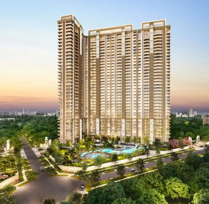 Tall residential building with modern architecture surrounded by greenery and roads at sunset.