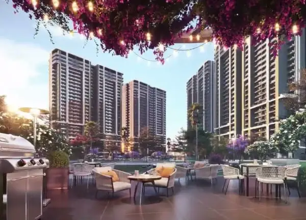 Outdoor seating area with tables, chairs, and a grill, surrounded by tall residential buildings.