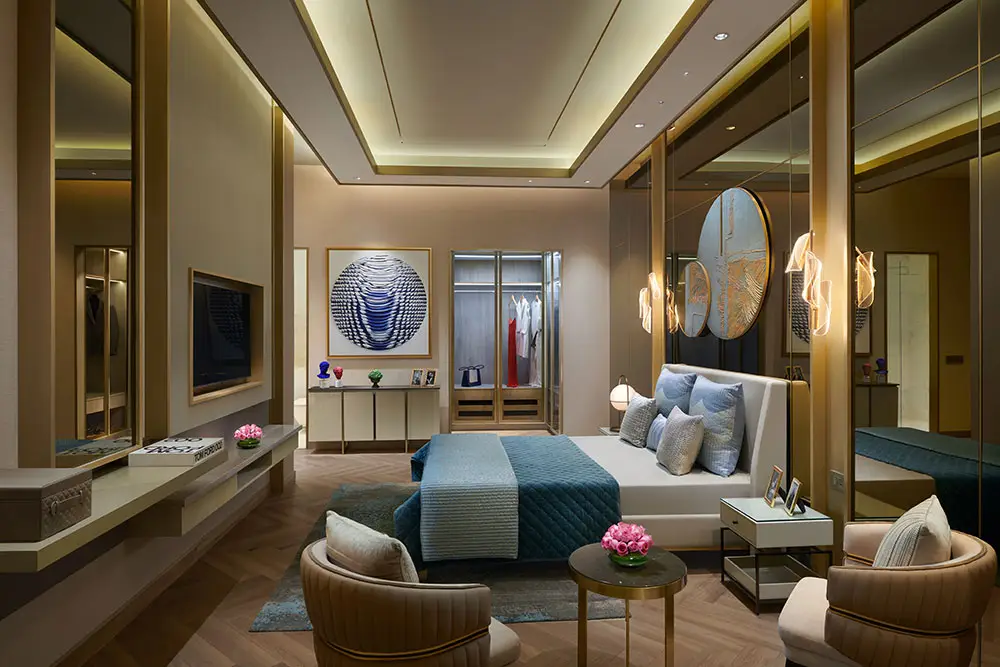 Stylish bedroom featuring a large bed, decorative mirrors, and elegant lighting.