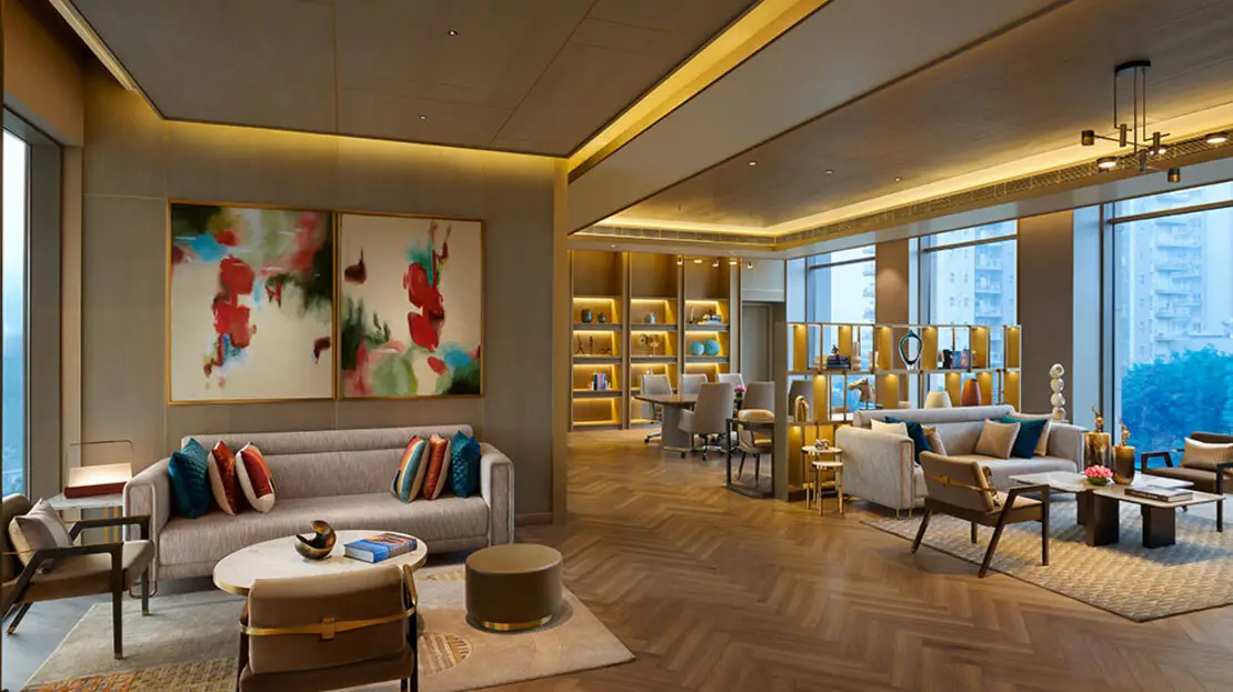 Contemporary lounge with colorful artwork, stylish furniture, and large windows offering city views.