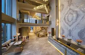 Spacious lobby featuring elegant furniture, marble walls, and a modern staircase with lighting.