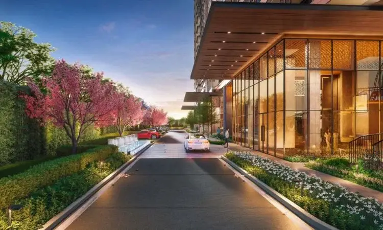 Modern building entrance with glass facade, cherry blossom trees, and cars on the driveway.
