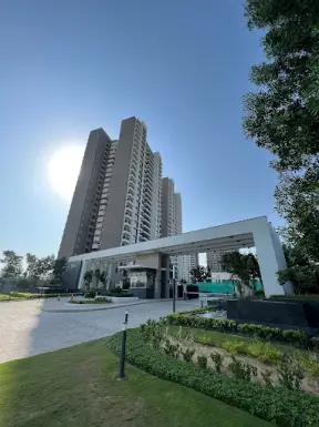 Tall residential building with modern architecture and landscaped entrance area under a clear blue sky.
