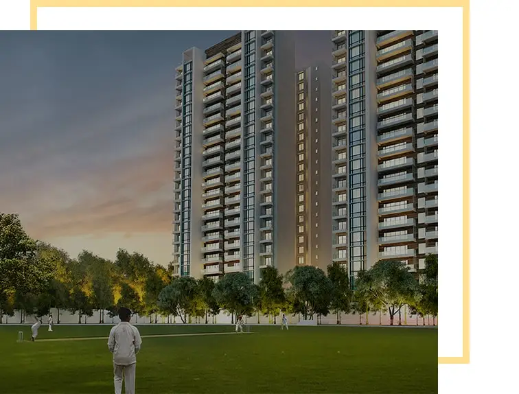 Modern residential towers with balconies surrounded by trees and a green field at dusk.