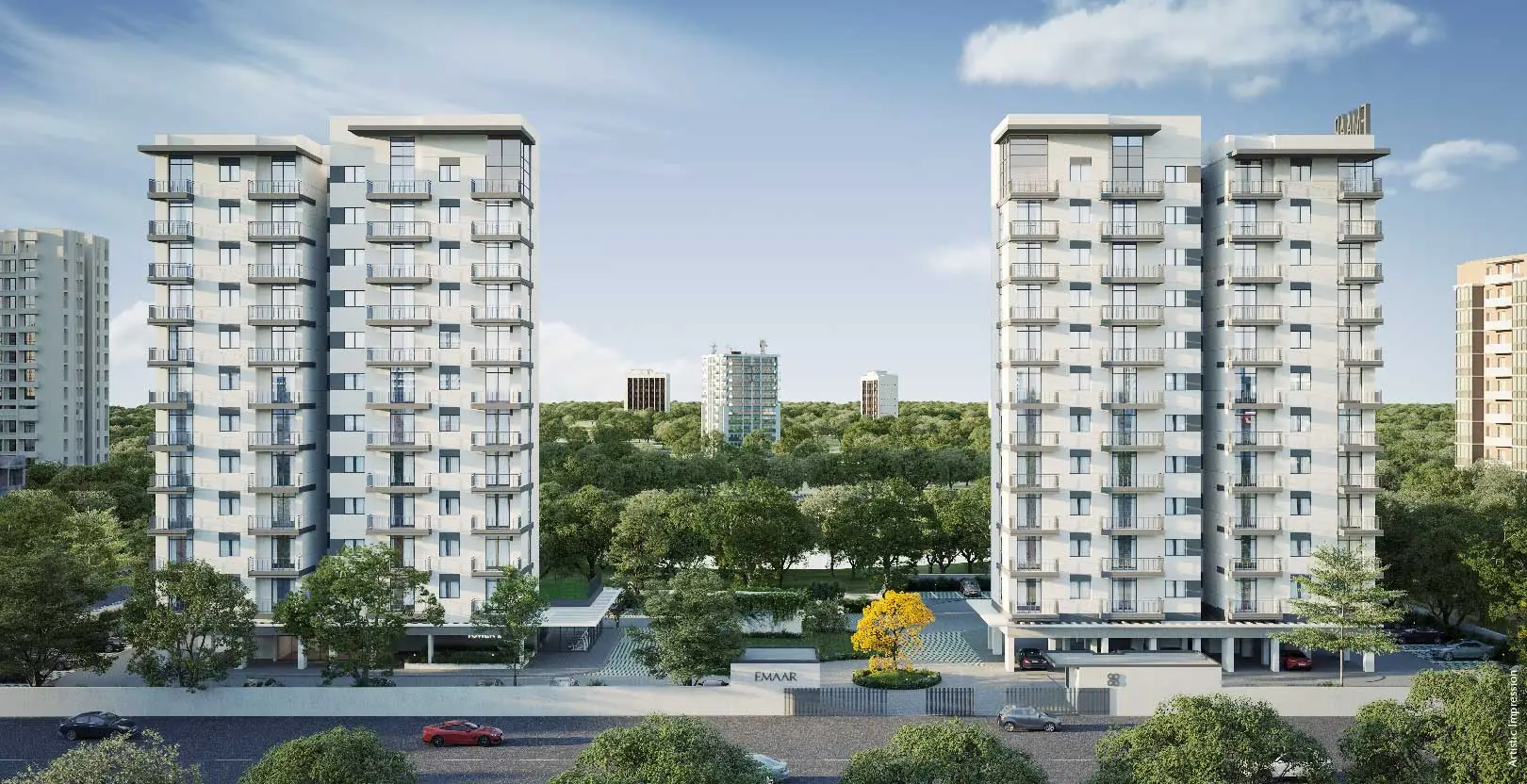 Two modern residential towers surrounded by trees and landscaped areas, with a clear blue sky.