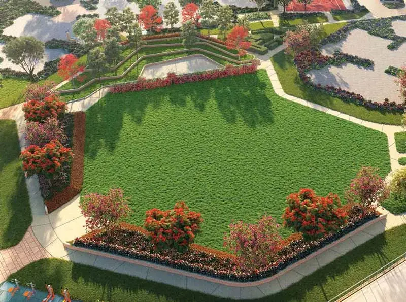 Aerial view of a landscaped park featuring green grass, flower beds, and walking paths.