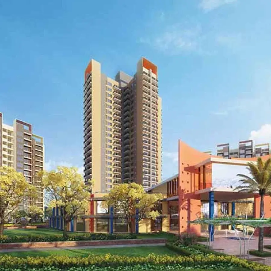 Modern residential towers with greenery and landscaped areas under a clear blue sky.