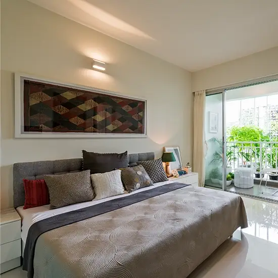 Stylish bedroom featuring a gray bed, decorative pillows, and a balcony with greenery.