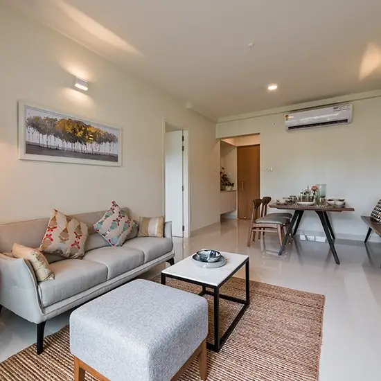 Modern living room with a gray sofa, decorative pillows, coffee table, and dining area.