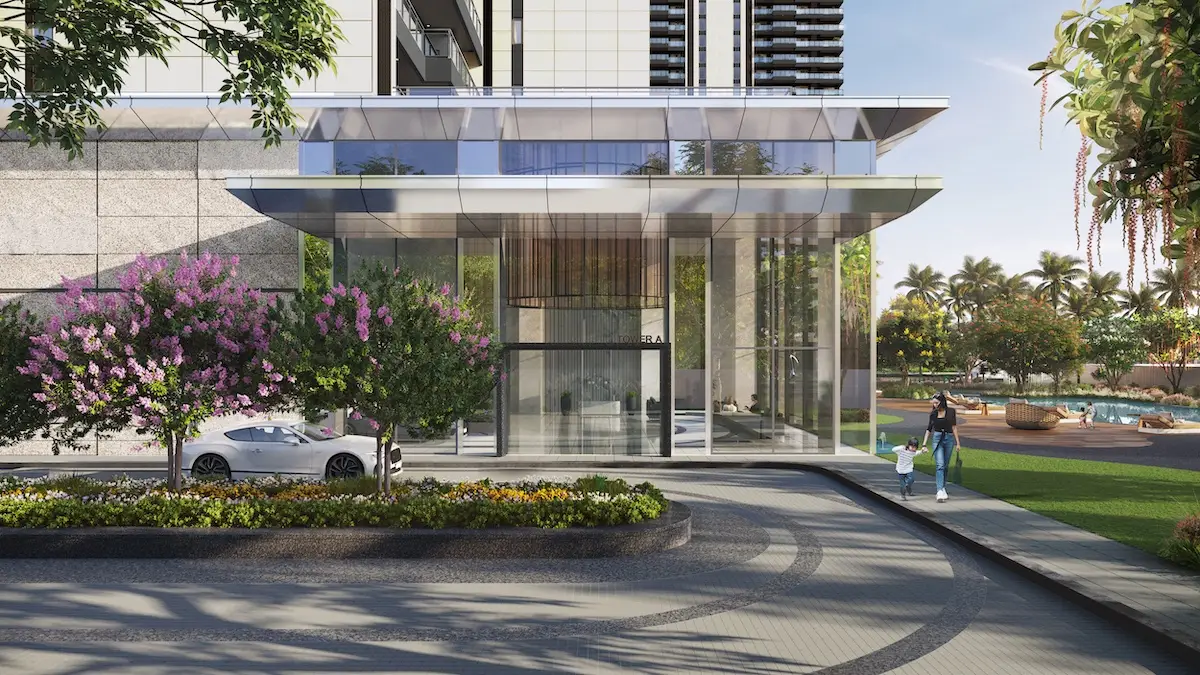 Glass entrance with flowering trees, a white car, and a family walking by lush greenery.
