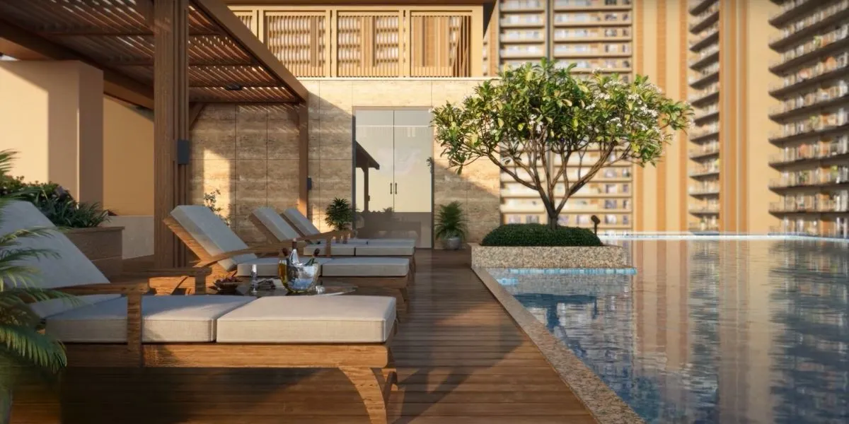 Wooden lounge chairs beside a swimming pool with a tree and greenery.