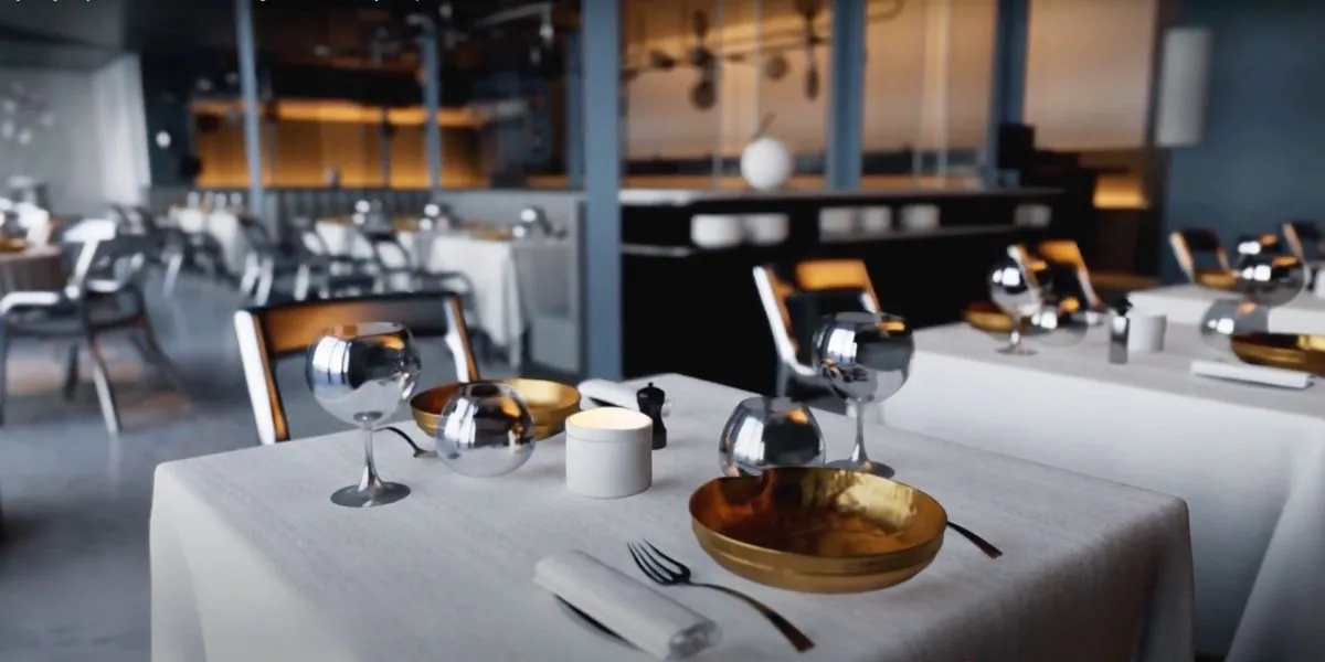 Elegant dining setup with silverware, glassware, and warm lighting in a modern restaurant.