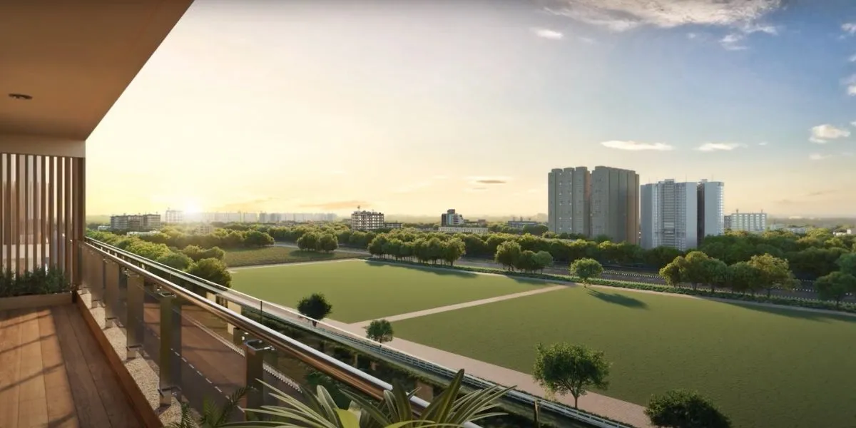Spacious balcony overlooking green fields and modern buildings under a clear sky.