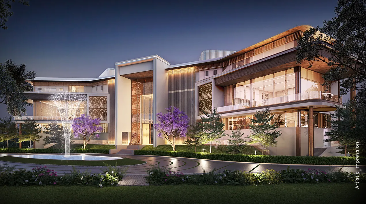 Contemporary building with large windows, surrounded by greenery and purple flowering trees at dusk.