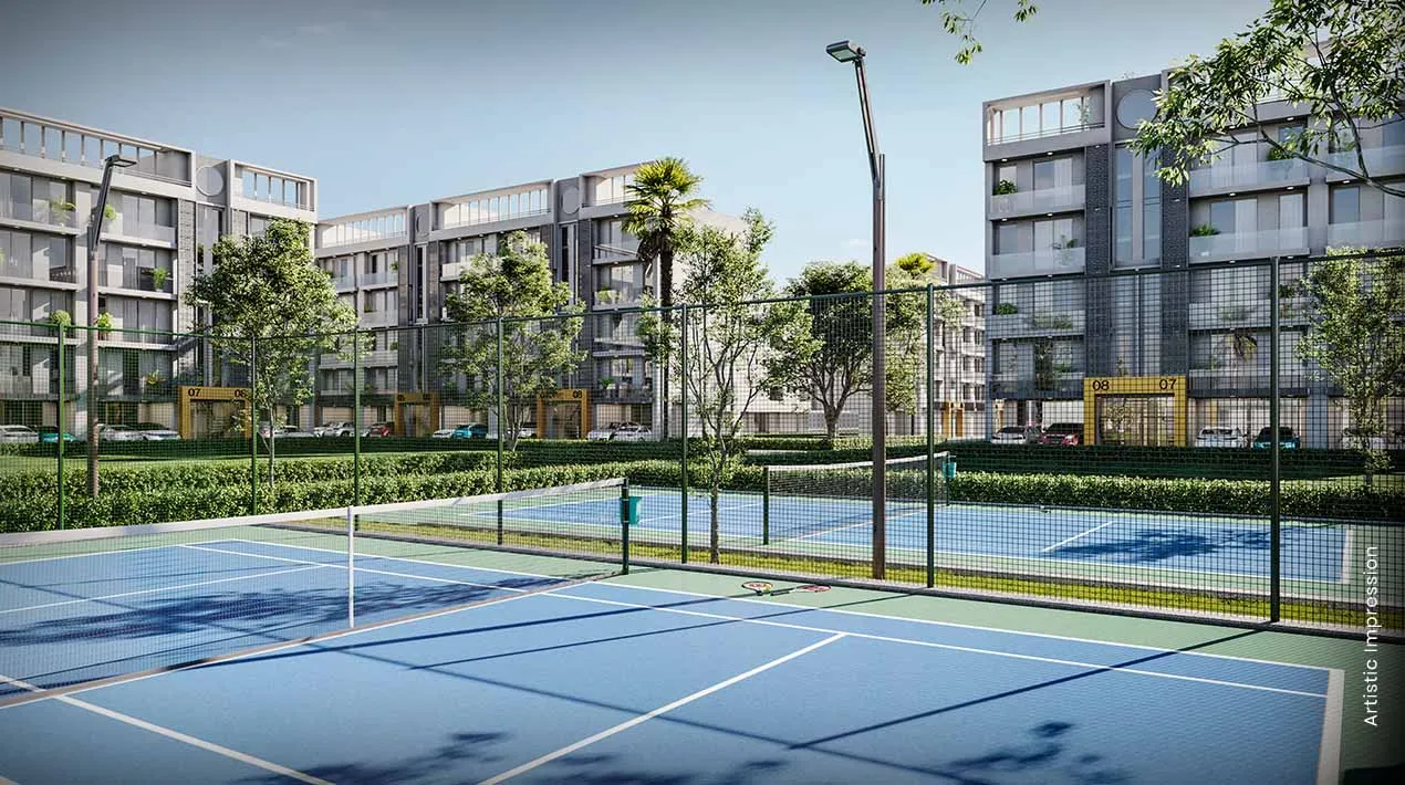 Two blue tennis courts surrounded by green landscaping and modern residential buildings.