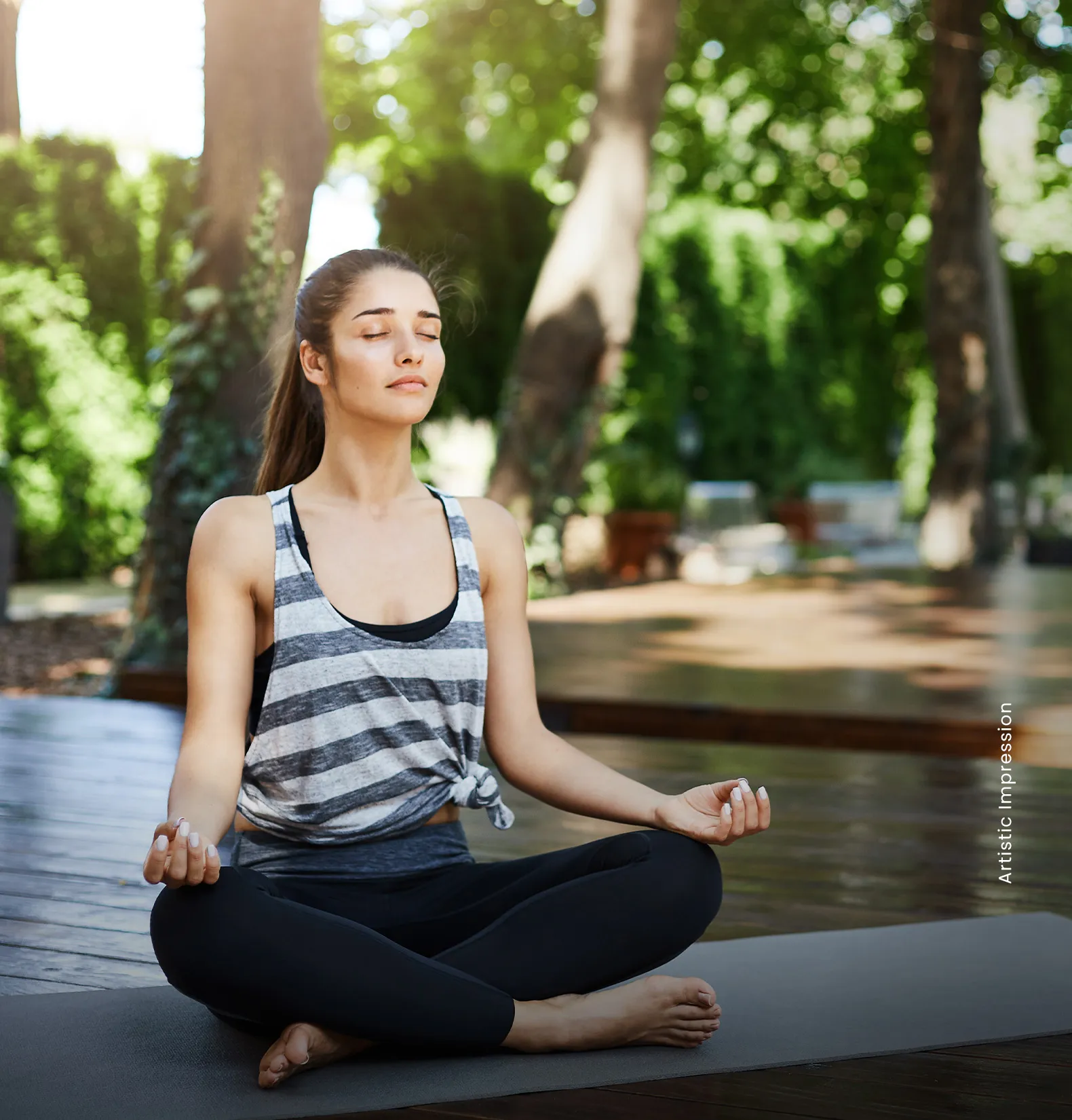 A woman in a striped tank top sits cross-legged on a yoga mat, eyes closed, in a serene