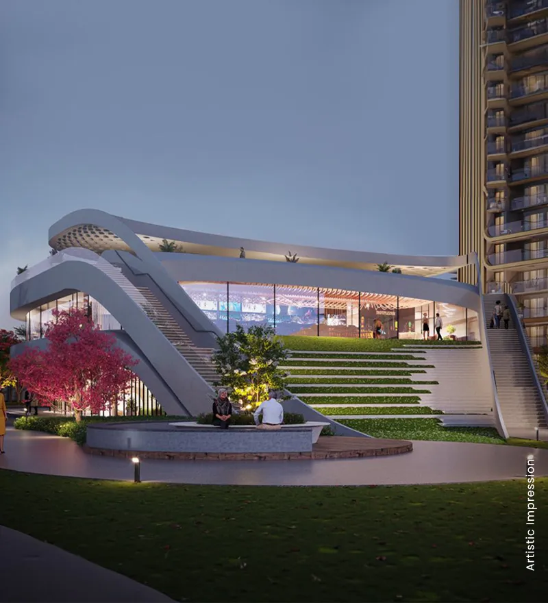 A contemporary building with curved stairs, glass facade, and landscaped greenery in the foreground.