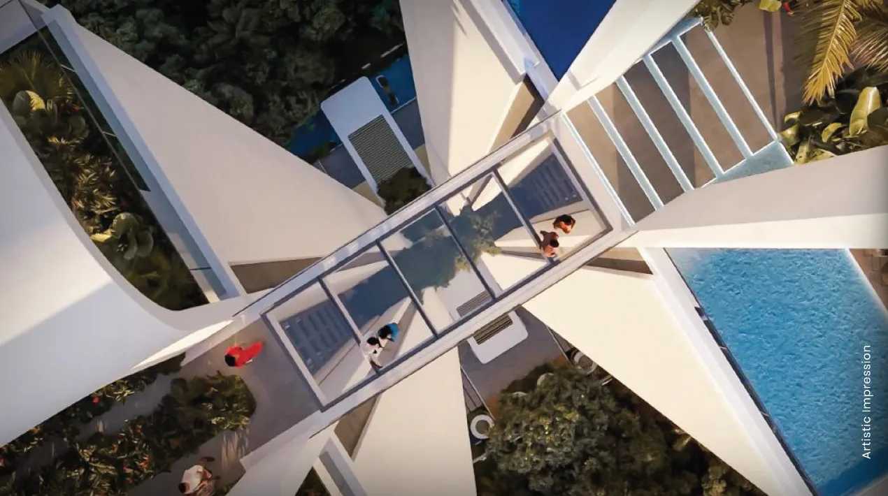 Aerial view of a glass air bridge connecting modern buildings surrounded by greenery and a swimming pool.