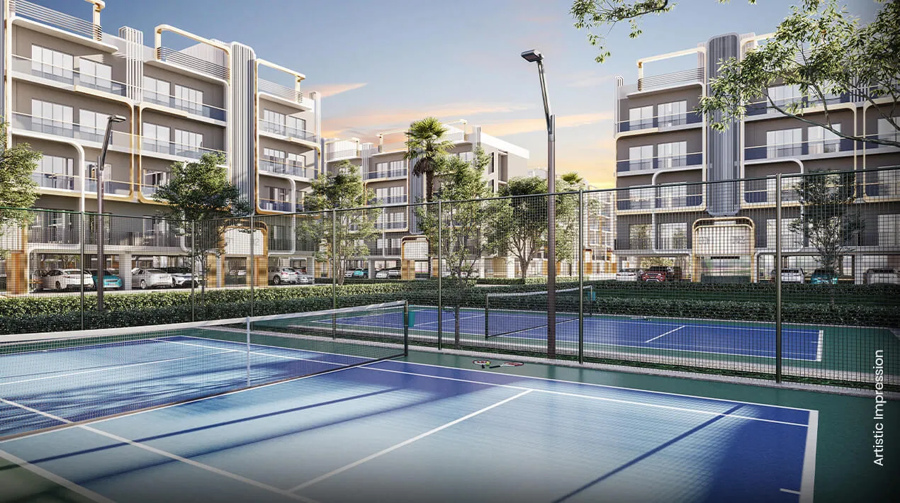 Two tennis courts surrounded by greenery and residential buildings in the background.