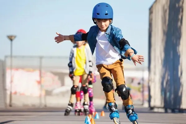 A young boy skating on a smooth surface, wearing a blue helmet and protective gear.