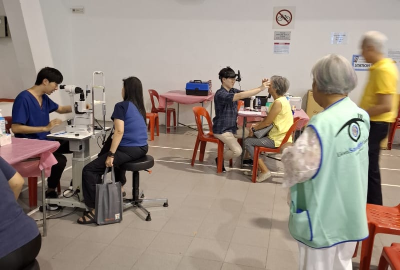 Doctor performing indirect ophthalmoscopy on an elderly participant