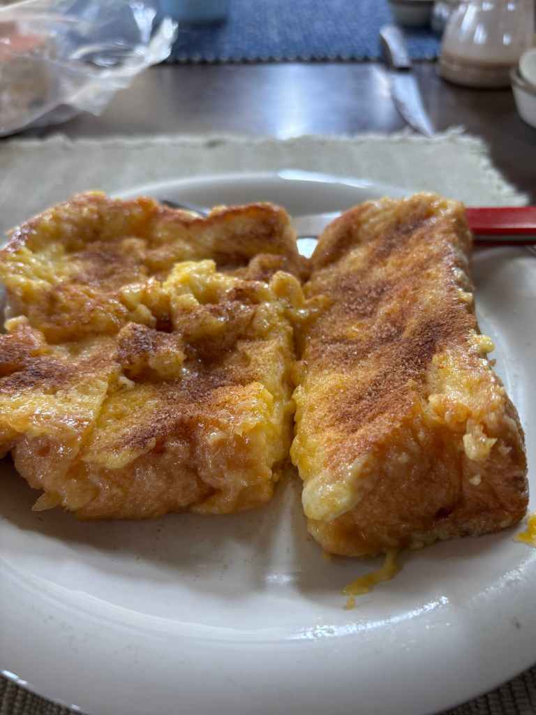 Plate of golden-brown, fluffy French toast slices, lightly dusted with cinnamon.