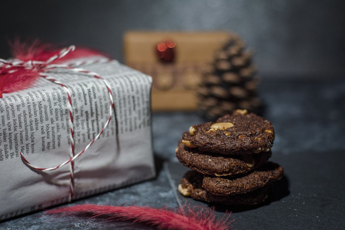 Cozy Christmas scene with rustic cookies, a wrapped gift, and festive decor on a dark background.